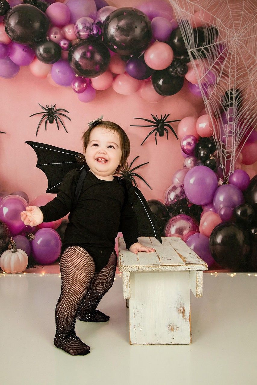 Little bat costume Halloween session with pink and black balloon garland